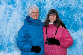 Pat and Rosemarie Keough in parkas infront of blue ice crevass